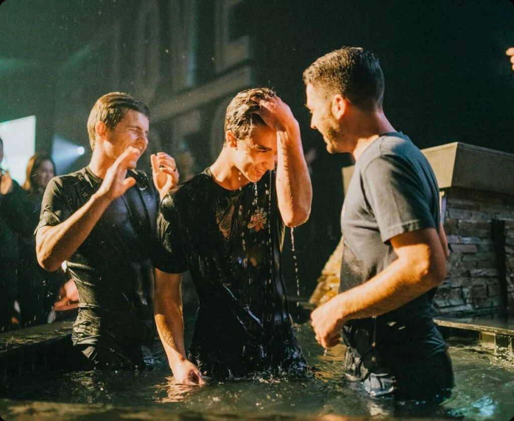 A man being baptized in the water with friends celebrating around him