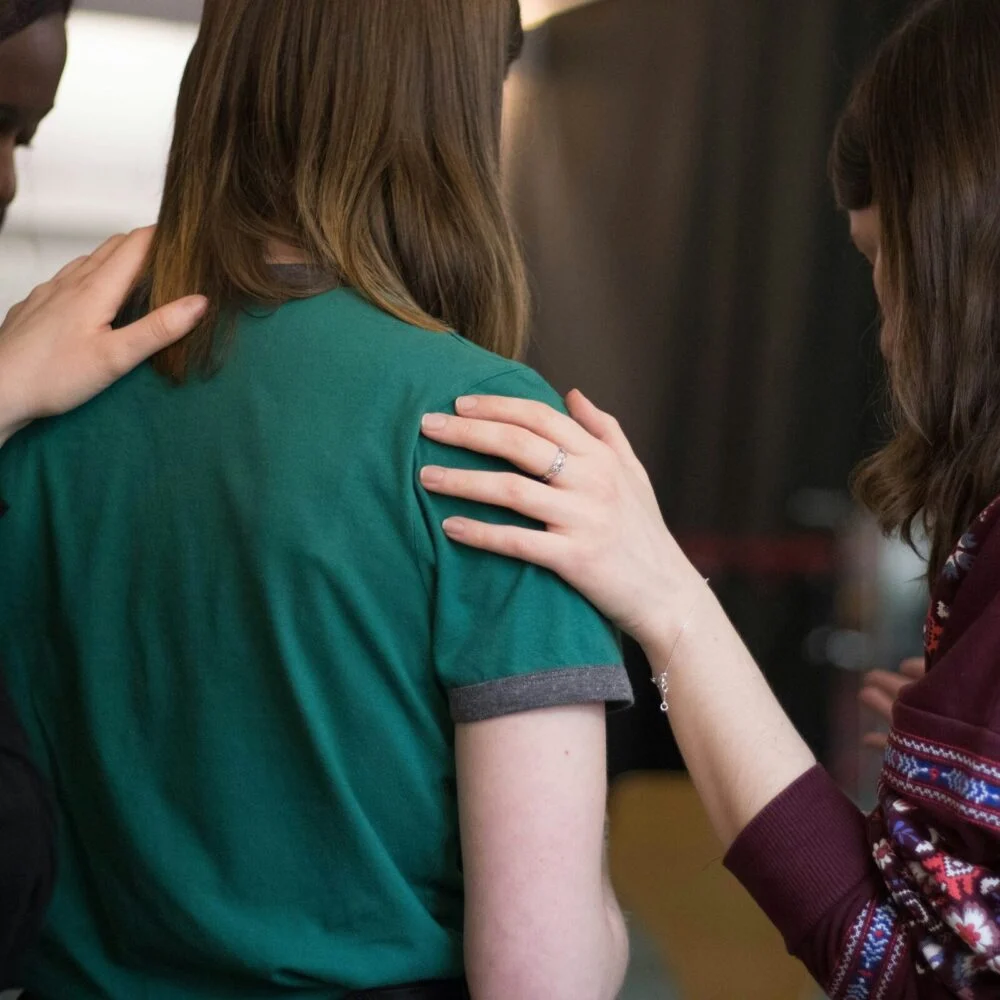 Church friends with their arms around each other in prayer